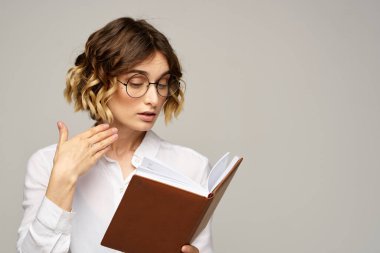 Elinde not defteri olan kadın iş hayatında bej arka plan gözlüklü saç stili.