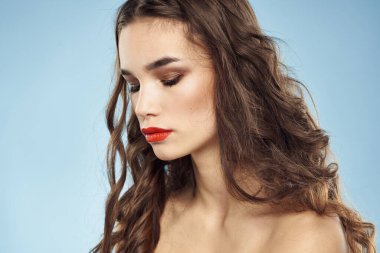 Güzel bir kadın. Çıplak omuzlar. Saç bakım, parlak makyaj, mavi arka plan.