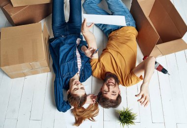Bir adam ve bir kadın yeni bir apartmanın zemininde kutular ve tamir aletleriyle.