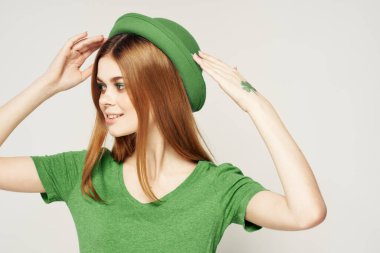 Yeşil elbiseli, arka planda şapkası olan bir kız St. Patrick Günü manzaralı.