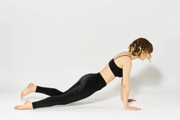 Sportive woman will do the exercise lying on the floor Gymnastics fitness in a bright room — Stock Photo, Image