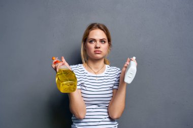 Temizlikçi kadın ellerinde deterjan tutarken servis gri arka planını kırpmış.