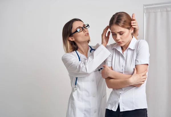 Professional doctor woman in glasses touches the head of the patient on a light background Stock Photo