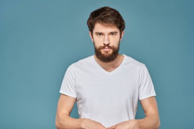 Beyaz tişörtlü, el kol hareketleri yapan, stüdyosu kesilmiş biri.