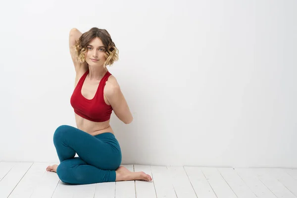 Mulher fazendo ioga comprimento total dentro de casa leggings azuis top tanque vermelho — Fotografia de Stock