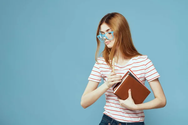 Ženské studentky s knihami v rukou na modrém pozadí a žluté brýle model účes oříznutý pohled — Stock fotografie