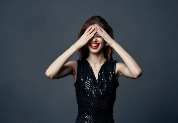 Emotionale Frau berührt ihren Kopf mit Händen und schwarzem Kleid Modell grauen Hintergrund — Stockfoto