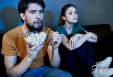 Bir erkek ve bir kadın akşam evde televizyon izliyorlar.