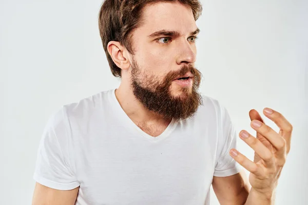 Homem barbudo gesticulando com as mãos corte vista branco t-shirt estúdio emoção luz fundo — Fotografia de Stock