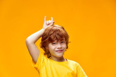 Kafasının üstünde boynuzları olan kızıl saçlı çocuk kameraya gülümsüyor. 