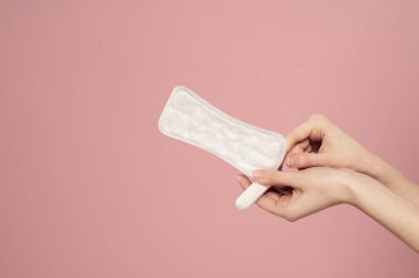Koruyucu ped ve tampon pembe arka plan regl günlerinde kadınların elinde.