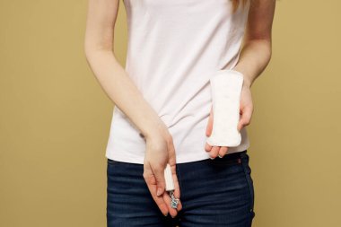 Elinde tampon ve bej arka planda pedi olan bir kız regl döneminin kritik günlerini gördü.