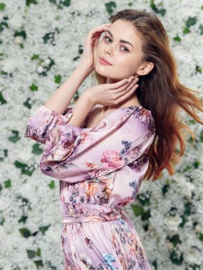 Güzel elbiseli kadın çiçek arkaplanının yanında el ele tutuşuyor. 