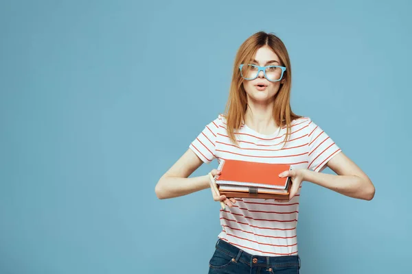 Dívka v módní brýle s notebooky v rukou na modrém pozadí oříznutý pohled kopírovat prostor — Stock fotografie