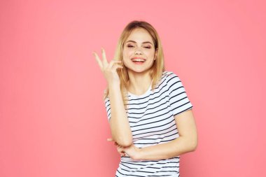 Neşeli kadın çizgili tişörtlü yaşam tarzı duyguları ve elleri pembe arka planlı jestler.