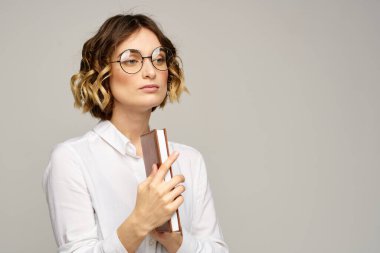 Elinde not defteri olan kadın iş hayatında bej arka plan gözlüklü saç stili.