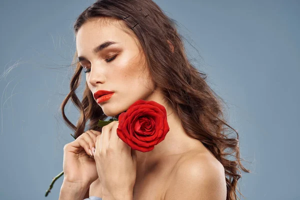 Portrét ženy s červenou růží v rukou na šedém pozadí nahá ramena večerní make-up — Stock fotografie