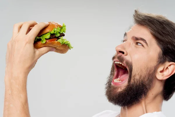 Hombre con hamburguesa comida rápida dieta amplia boca abierta — Foto de Stock