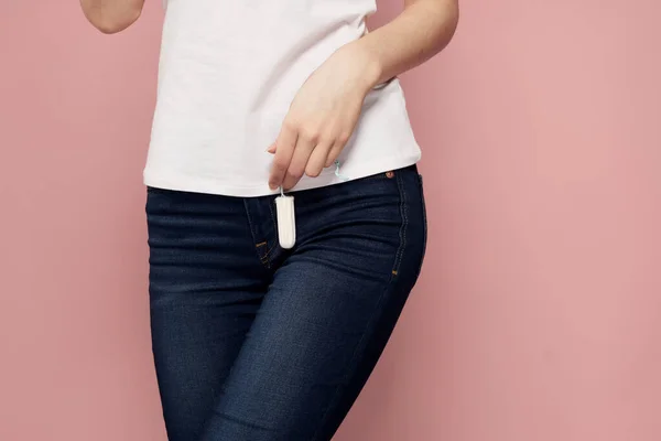 Žena s tampónem v ruce kritické dny hygiena bílá tričko džíny růžové pozadí menstruační cyklus — Stock fotografie