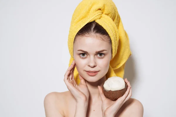 Wanita dalam handuk kuning di kepalanya kelapa di tangannya Exotics kulit bersih kosmetik alam — Stok Foto