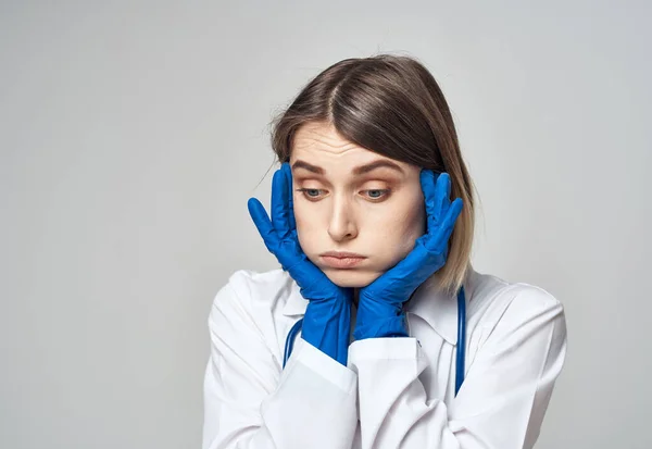 Медсестра в медицинском халате и синих перчатках жесты со стетоскопом вокруг шеи — стоковое фото