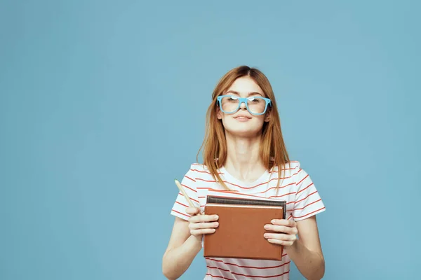 Étudiante avec des livres dans les mains sur un fond bleu et modèle de lunettes jaunes coiffure vue recadrée — Photo