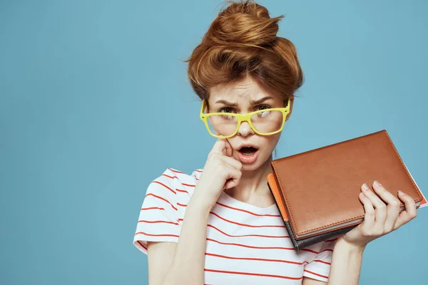 Étudiante avec bloc-notes et coiffure de lunettes sur son professeur principal modèle fond bleu — Photo