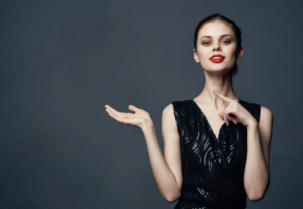 Mujer muestra sus manos a un lado en un fondo gris emociones modelo de publicidad — Foto de Stock