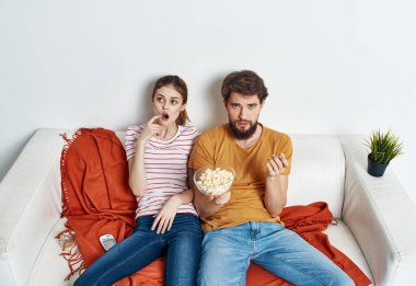 Evli çift kanepede patlamış mısır izliyor.