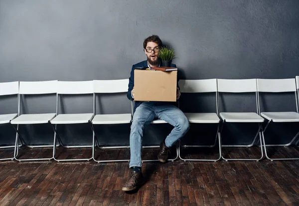 Man sitting on white chair waiting for lighting box job search depression