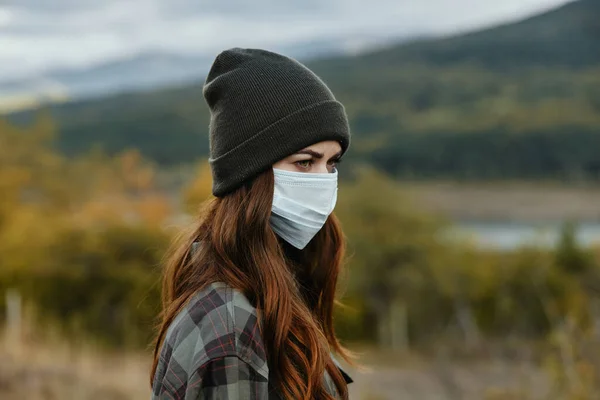 Maski medyczne i w ciepłej czapce są patrząc na bok na przyrodę w lesie — Zdjęcie stockowe