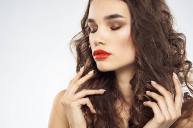 Çıplak omuzlu, dalgalı saç stili, göz alıcı makyaj lambası arka planı olan bir kadın.