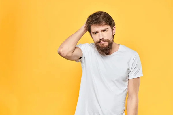 Barbudo hombre en una camiseta blanca gestos con las manos emociones estudio fondo amarillo — Foto de Stock