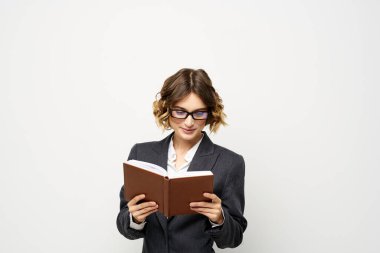 Not defteri ve gözlüklü bir iş kadını takım elbise modelinin hafif arka planında çalışıyor..