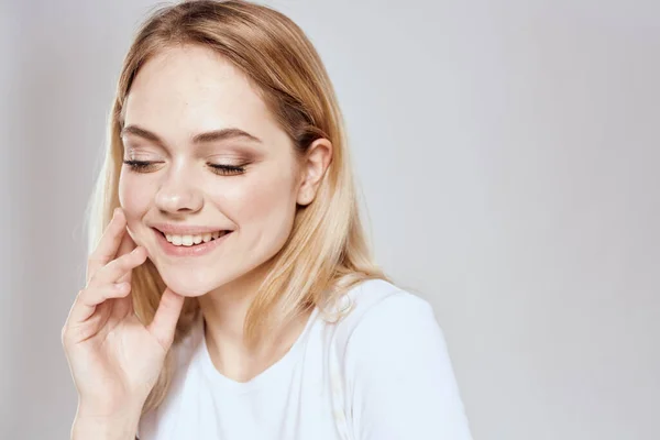 Mulher loira alegre em branco t-shirt recortada vista luz fundo — Fotografia de Stock