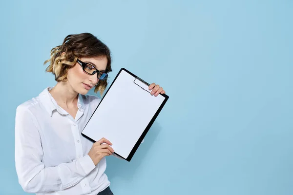 Ділова жінка з документами в папці на синьому фоні і в легких сорочках окулярах на обличчі — стокове фото