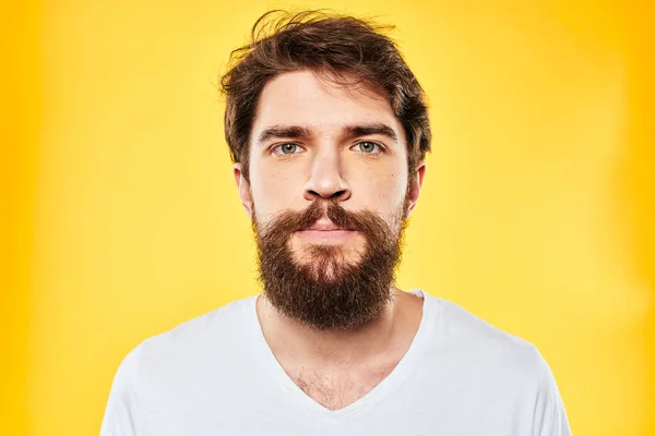 Emotionele bebaarde man in t-shirt bijgesneden uitzicht gele achtergrond studio — Stockfoto