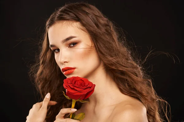 Nő egy piros rózsa egy sötét háttér hosszú haj smink piros ajkak — Stock Fotó