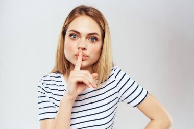 Çizgili tişörtlü duygusal kadın, elleri yaşam tarzı hafif arka planlı.