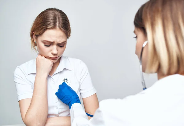 Un patient s'assoit sur une chaise et une femme médecin avec un stéthoscope — Photo