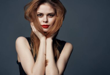 Kızıl saçlı, siyah elbiseli, kırmızı dudaklı ve göz farlı bir kadın.