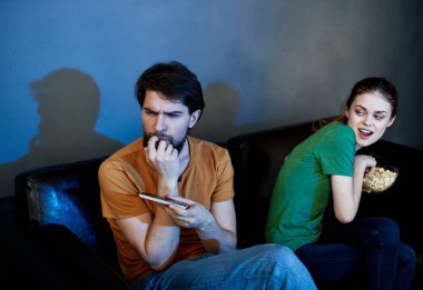 Cep telefonu olan bir adam ve akşam evde televizyon izleyen güzel bir kadın.