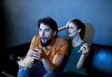 Korkmuş kadın ve adam akşam televizyon karşısında kanepede film izliyorlar.