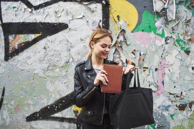 Sokakta kitap okuyan mutlu bir kadın duvardaki duvar yazısının yanında.