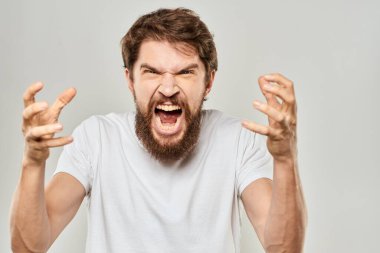 Sakallı bir adam elleri beyaz tişörtlü agresiflik arka planında hareket ediyor.
