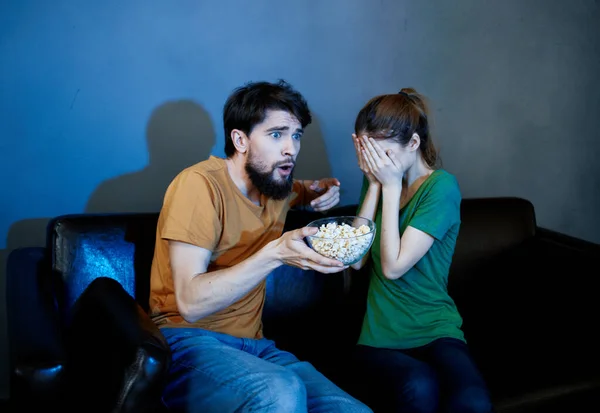 Перелякана жінка і чоловік дивиться фільм ввечері перед телевізором на дивані — стокове фото