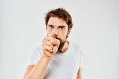 El kol hareketleri yapan sakallı bir adam. Beyaz tişört, stüdyo, duygu, ışık arka plan.