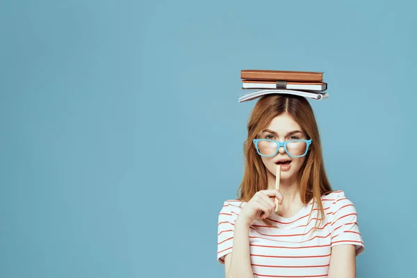 Женщина-студентка с книгами на голове научного образования синий фон эмоции жестом руками — стоковое фото