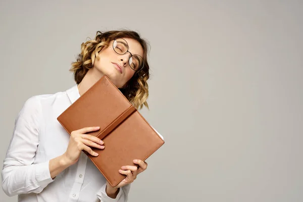 Donna d'affari con blocco note e occhiali su sfondo chiaro acconciatura emozioni di successo — Foto Stock