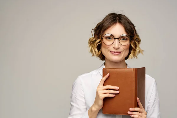 Femme avec bloc-notes dans les mains travail d'affaires beige fond lunettes coiffure — Photo